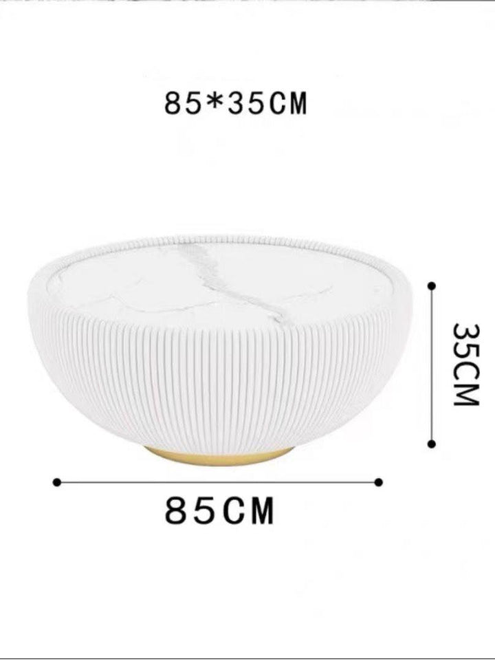 What size coffee table is best for a modern living room? This round white coffee table with ribbed detailing measures 85 cm in diameter and 35 cm in height, making it an ideal choice for contemporary spaces. The table features a sleek gold base and a minimalist design, perfect for adding both functionality and style to your living room.