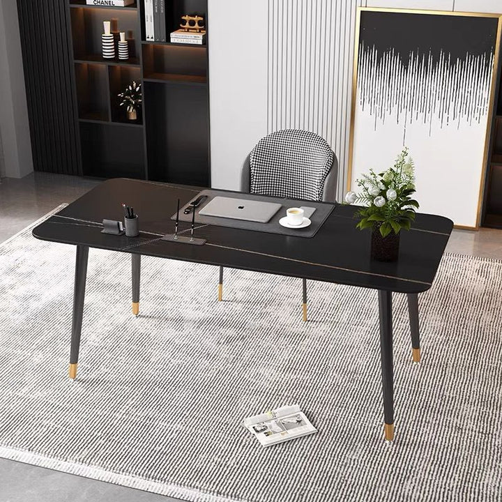 "What are the best modern desks for a home office? This sleek black desk with gold accents provides a stylish and functional workspace. Paired with a houndstooth-patterned chair, the office setup includes a laptop and minimalistic decor, creating a clean and sophisticated home office environment.