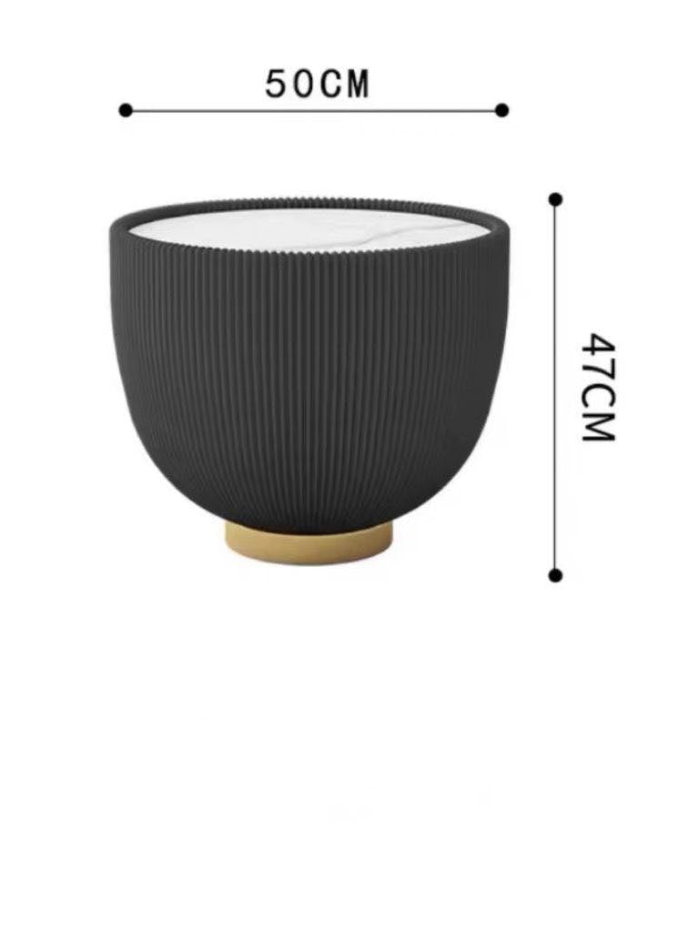 How tall should a coffee table be for a living room? This modern black coffee table with ribbed detailing measures 50 cm in diameter and 47 cm in height, making it a perfect accent piece for contemporary living spaces. The table features a gold base, adding a touch of luxury while maintaining functionality.