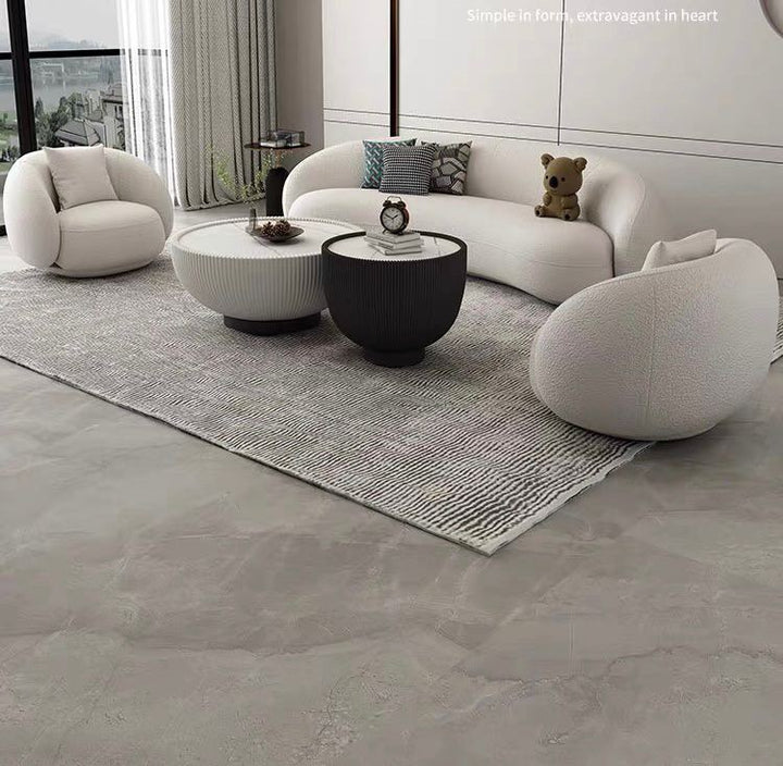 What are the best modern coffee tables for a living room? This stylish setup features two ribbed round coffee tables—one white and one black—with elegant gold bases. The tables are decorated with minimalistic items and placed in front of a cozy white sofa with accent pillows, combining functionality and style for a contemporary living room.