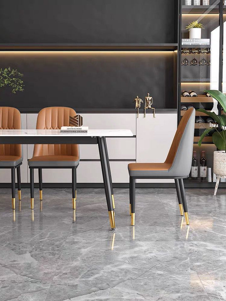 What are the best chairs for a modern marble dining table? This dining room features tan upholstered chairs with black legs and gold accents, paired with a sleek white marble table. The modern design is enhanced by a black and white backdrop with minimalist decor, creating an elegant and sophisticated dining space.