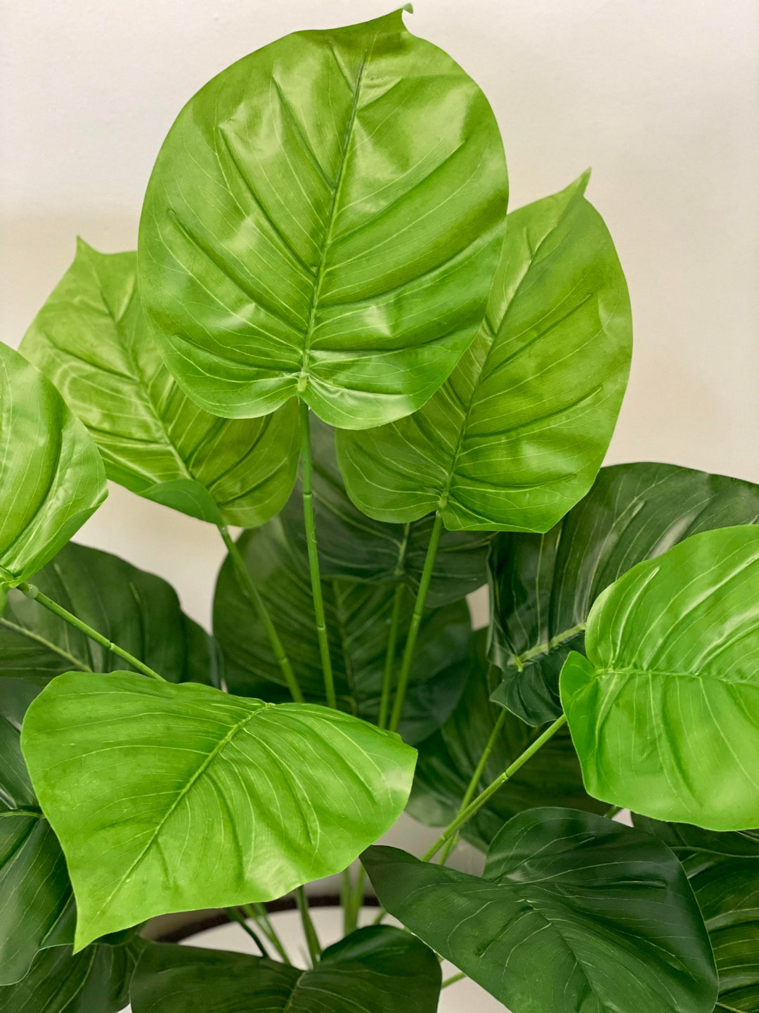 Realistic artificial tropical plant in black pot, featuring large green leaves, ideal for modern home and office decoration.