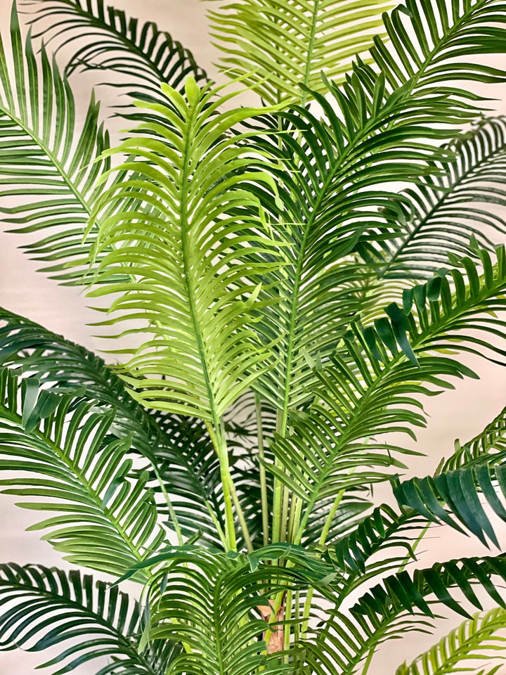 Close-up of vibrant green artificial palm leaves, showcasing their detailed texture and lush tropical aesthetic, perfect for enhancing indoor decor with a natural touch.