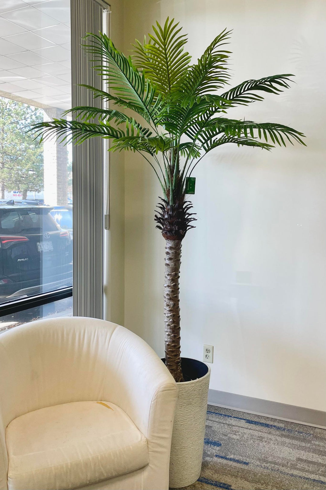 A life-sized artificial palm tree featuring a sturdy trunk and vibrant green leaves, ideal for creating a tropical atmosphere indoors.