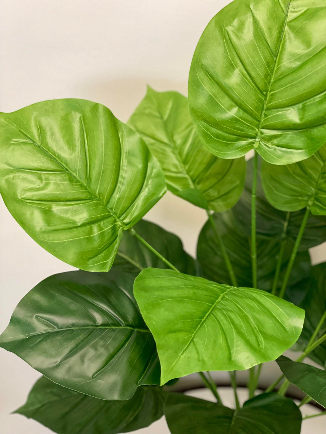 Close-up of large, glossy green artificial leaves, perfect for home decor and indoor plant arrangements.