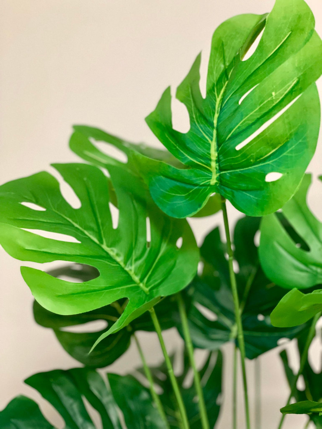 Close-up of artificial Monstera leaves showcasing intricate split leaf design, ideal for home or office decor.