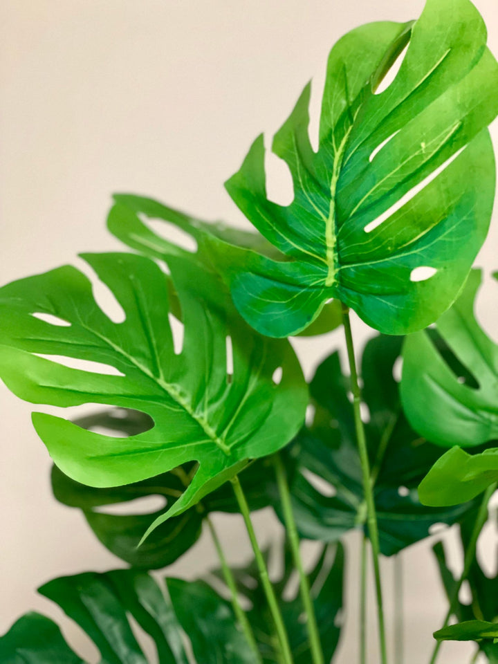 Close-up of artificial Monstera leaves showcasing intricate split leaf design, ideal for home or office decor.