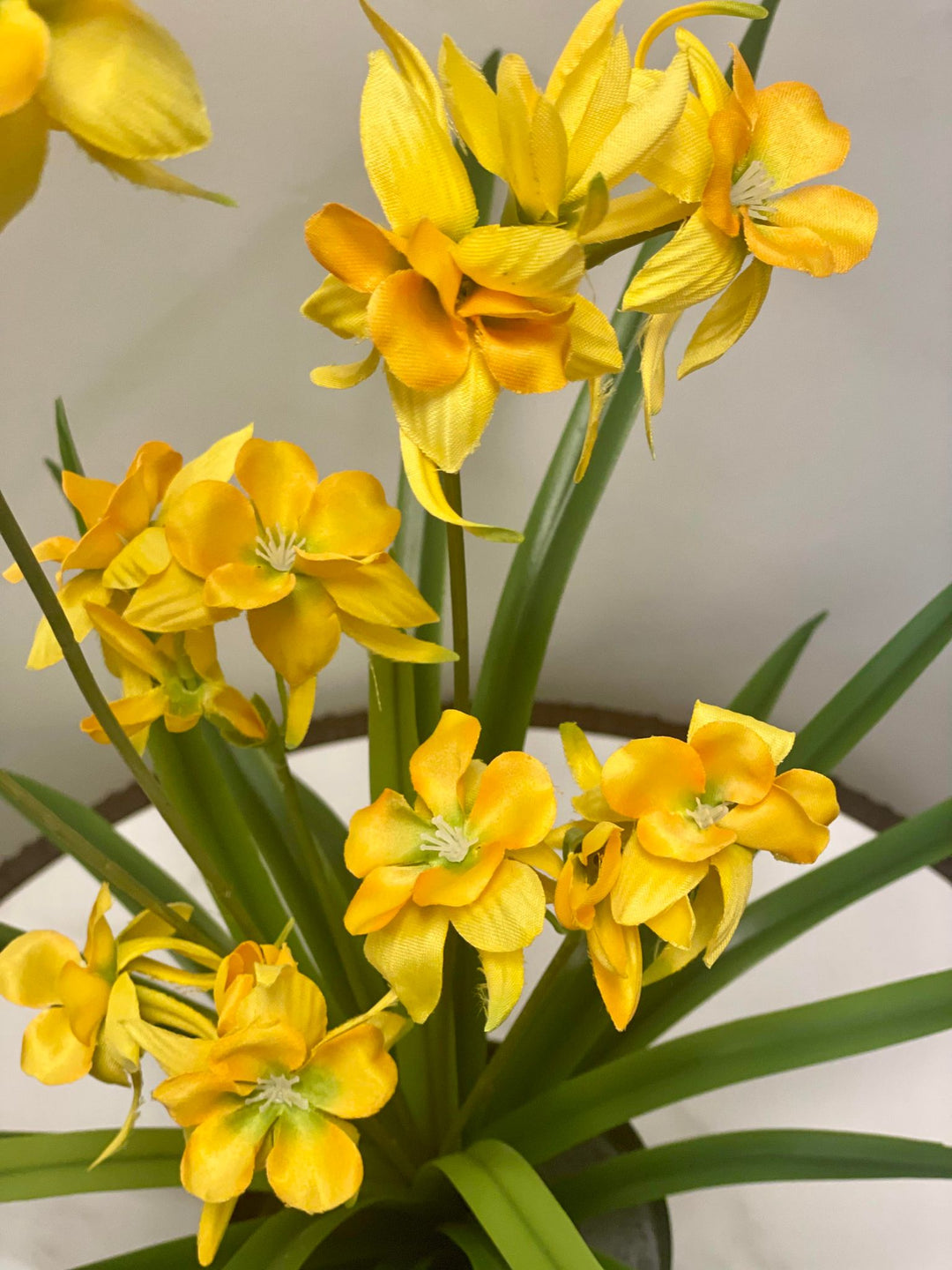 Close-up of yellow orchid flowers, showcasing their delicate fabric petals with soft green stems and leaves in the background.