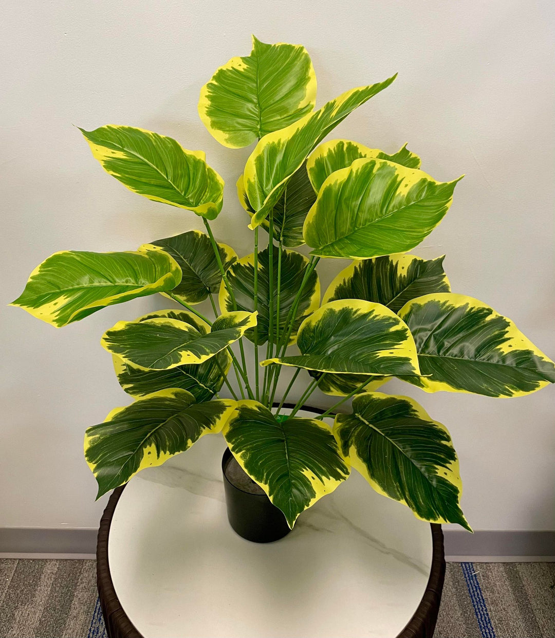 Vibrant yellow and green artificial leaves arrangement in a black pot, ideal for brightening indoor spaces.