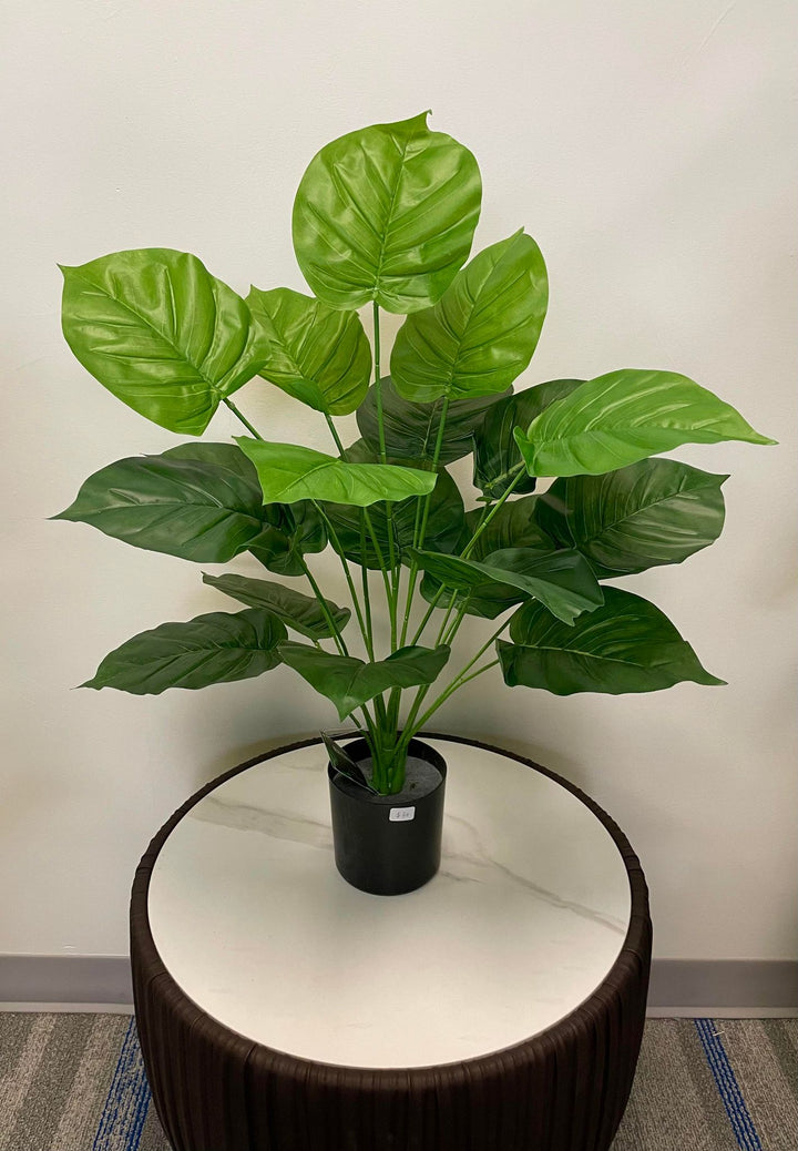 Realistic artificial tropical plant in black pot, featuring large green leaves, ideal for modern home and office decoration.