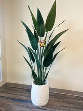 Load image into Gallery viewer, White geometric-textured planter holding a tall artificial bird of paradise plant with vibrant green leaves and orange flowers, placed indoors on a carpeted floor. Is this planter lightweight and easy to reposition?
