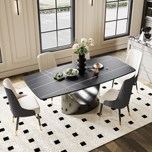 Charger l&#39;image dans la galerie, Contemporary Dining Table with a Sleek Black Surface and Unique Curved Metal Base, Adorned with Floral Centerpiece and Dishware, Surrounded by Stylish Upholstered Chairs in a Bright Dining Room with Large Windows and a Geometric Patterned Rug

