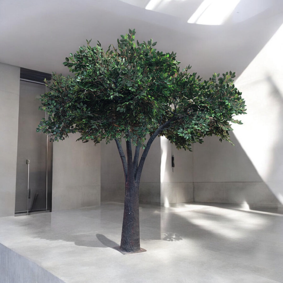 Artificial tree with a lifelike trunk and lush green foliage, positioned in a minimalist indoor venue, perfect for adding a natural touch to modern wedding and event decor. Can these rental trees be used to create a focal point for event photography?