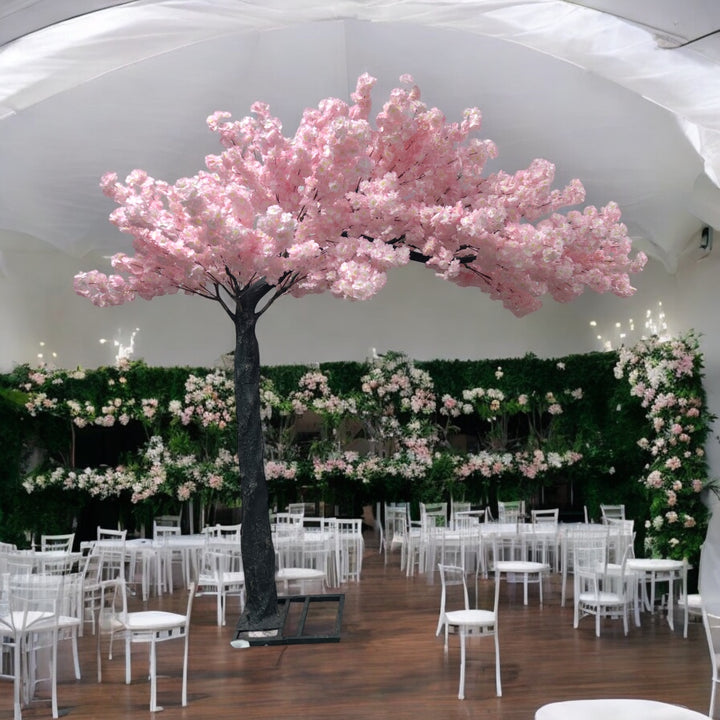 Elegant artificial cherry blossom tree with pink flowers, perfectly placed amidst a lavishly decorated wedding venue featuring pink floral arrangements and cascading fairy lights. Can this artificial tree be customized to match different event themes?