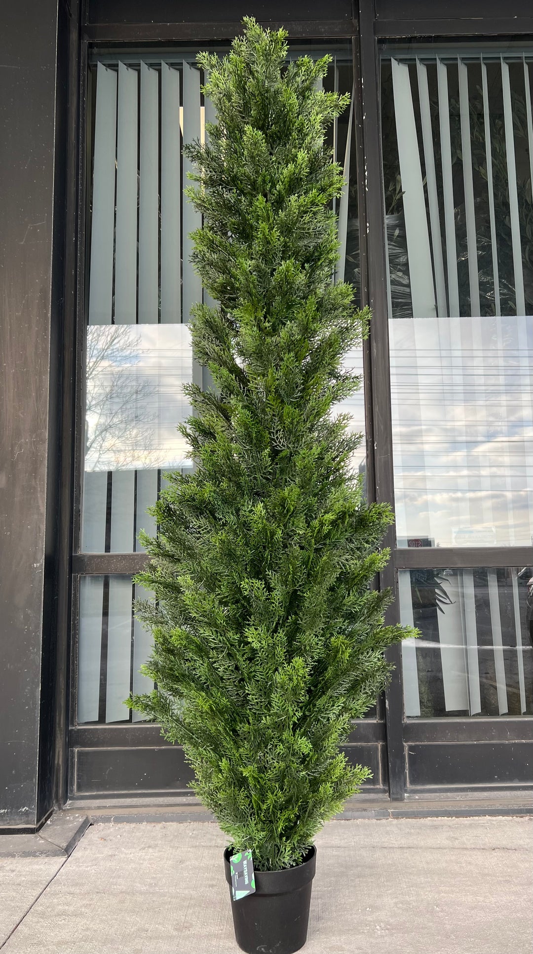 Artificial tall evergreen plant in a black pot, featuring lush green foliage with subtle yellow accents, perfect for outdoor or indoor decor.