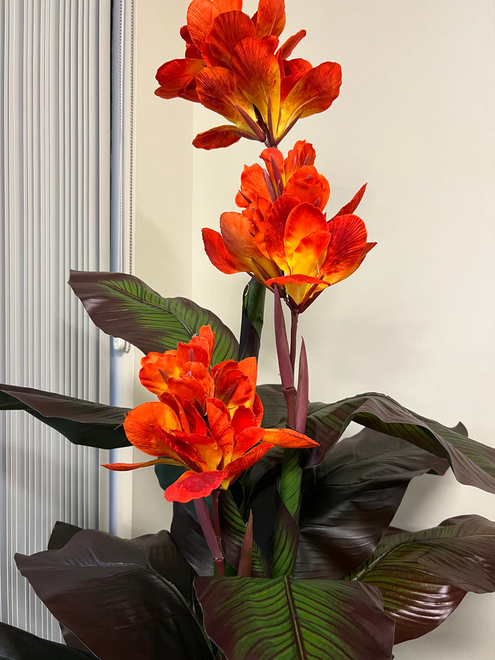 Artificial tropical canna lily plant with striking orange flowers and deep green leaves with detailed veining, creating a vibrant and exotic accent for indoor decor.