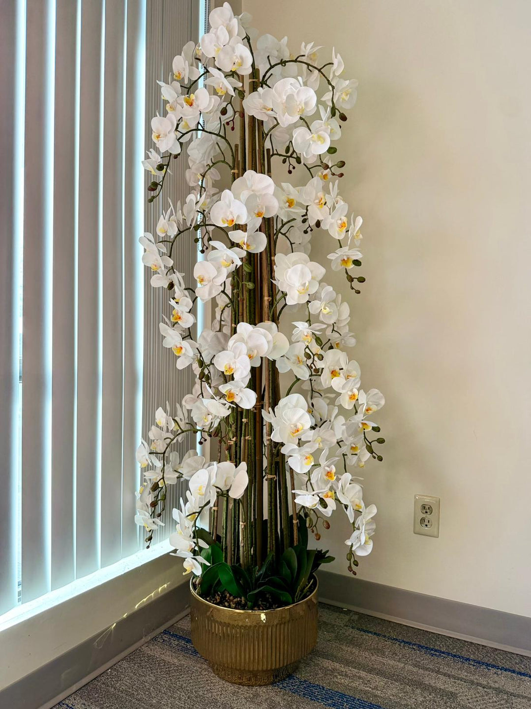 5.6ft artificial orchid arrangement with realistic orchid flowers placed in a beautiful gold vase on a carpeted floor.