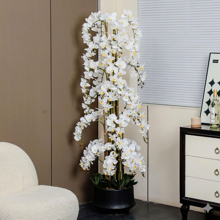 Artificial white orchid plant in a room setting with a chair and dresser.