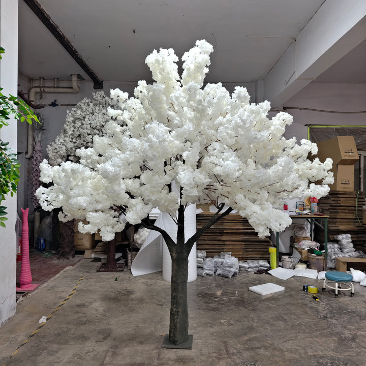 An artificial 8ft white cherry blossom tree with soft white flowers displayed inside warehouse.