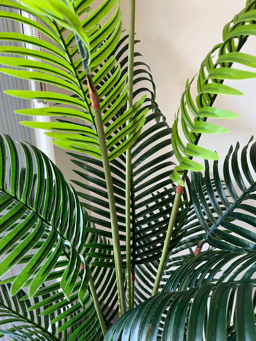 Close-up of artificial palm fronds, showcasing vibrant green leaves and realistic detailing, ideal for indoor decoration.