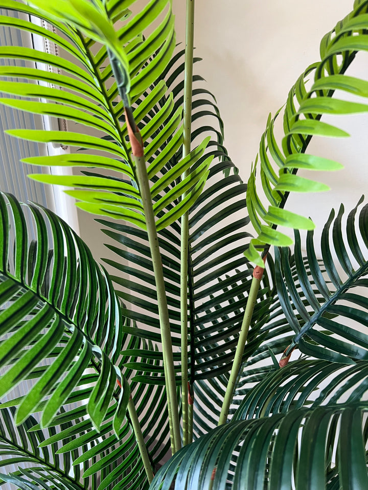 Close-up of artificial palm fronds, showcasing vibrant green leaves and realistic detailing, ideal for indoor decoration.