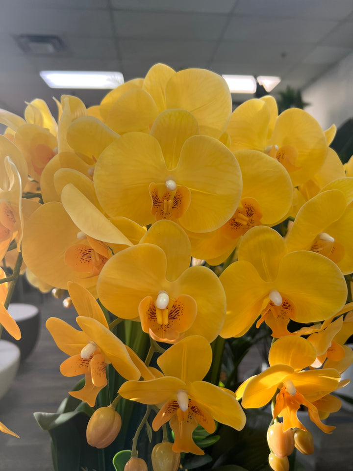 A close-up of artificial yellow-speckled orchid flowers with realistic details. How do I maintain the vibrant colors of artificial flowers over time?