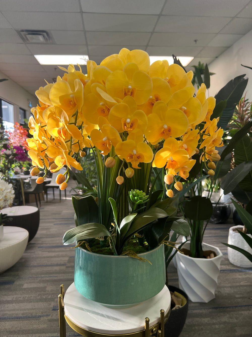 A bright arrangement of artificial yellow orchids with lifelike petals and stems in a glossy turquoise pot. What are the best ways to clean artificial plants without damaging them?