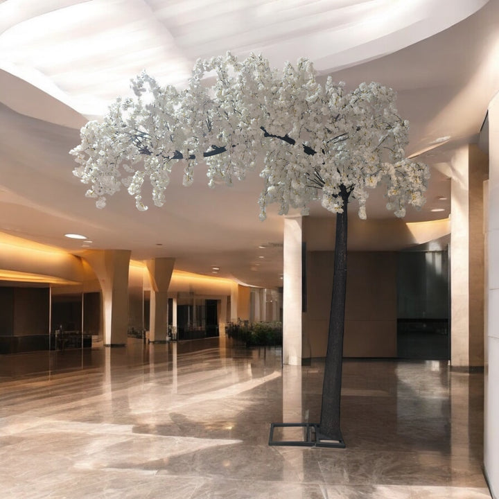Decorative trees with white flowers in a large indoor space with high ceilings.