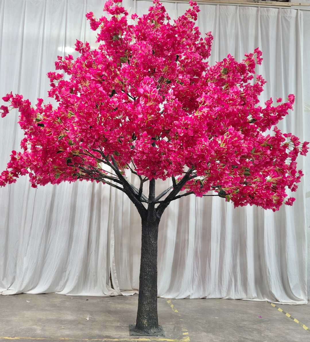 Close-up of pink bougainvillea blossoms on an 8ft faux tree in front of a white drapey backdrop.