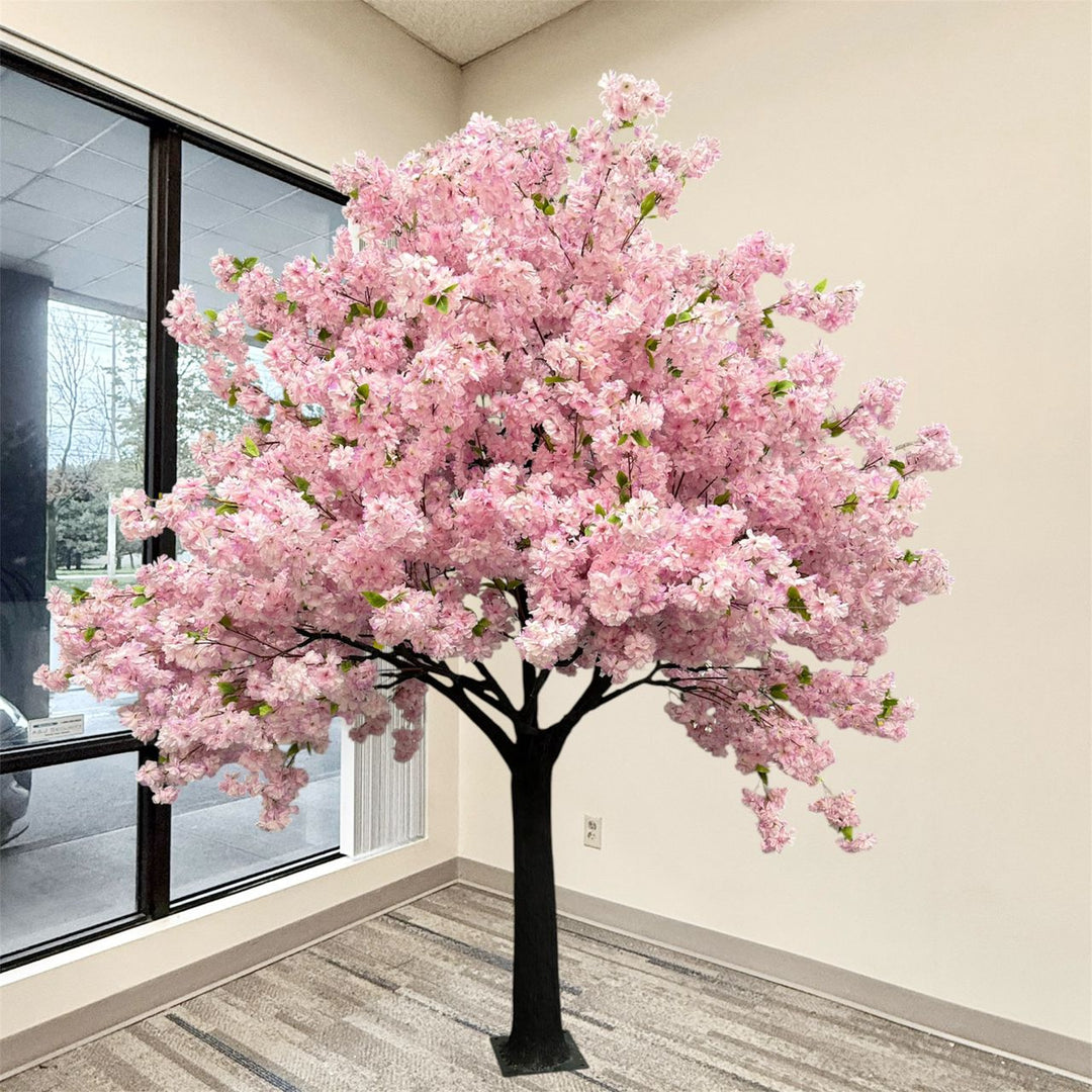 8ft artificial purple cherry blossom tree with dense purple flowers and a black trunk, displayed indoors near a window in a room with beige walls and gray patterned carpet.