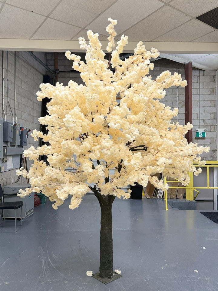 Decorative artificial off white cherry blossom tree in an indoor setting with a plain background