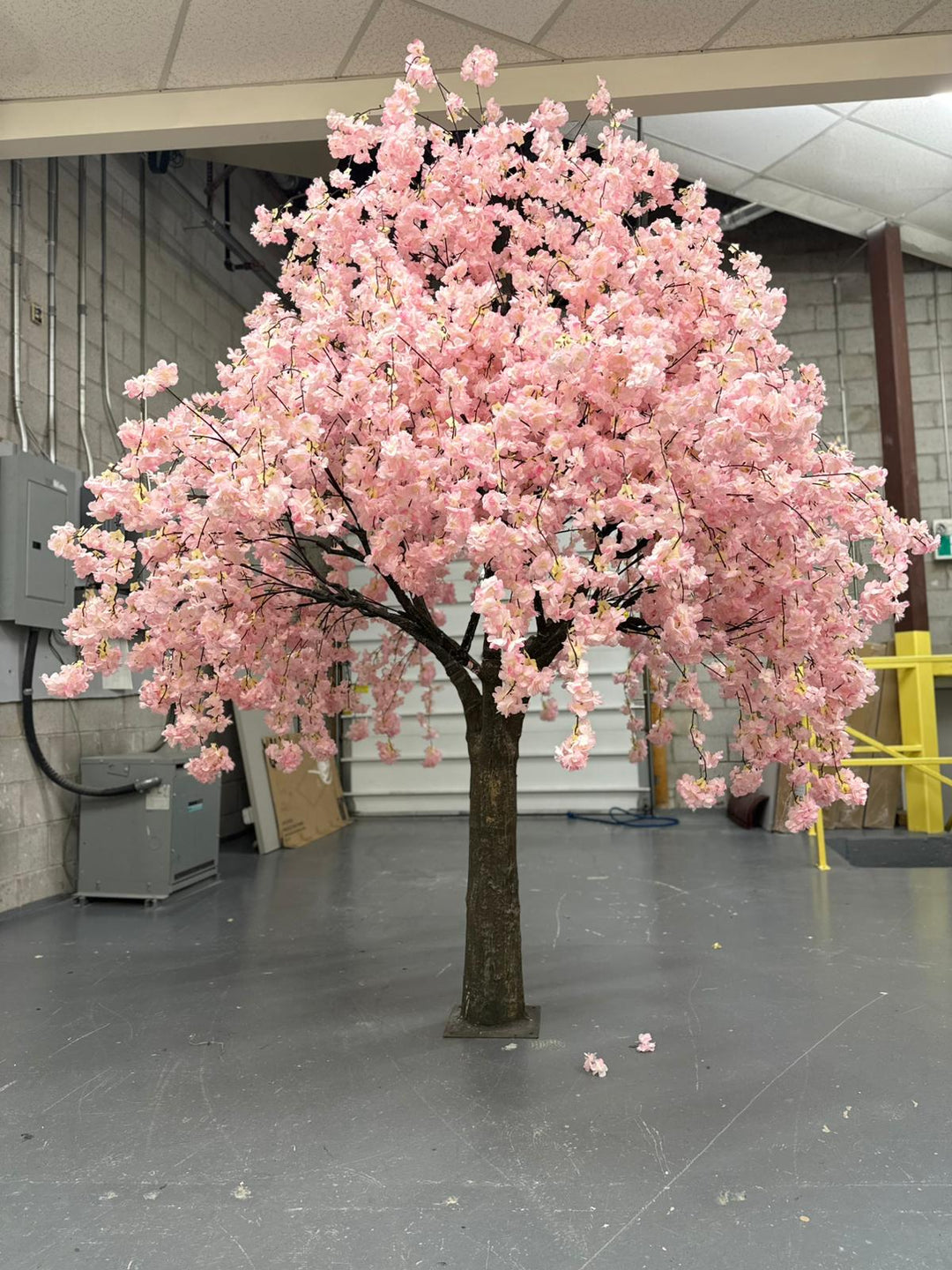Pink artificial weeping cherry blossom tree in a warehouse setting