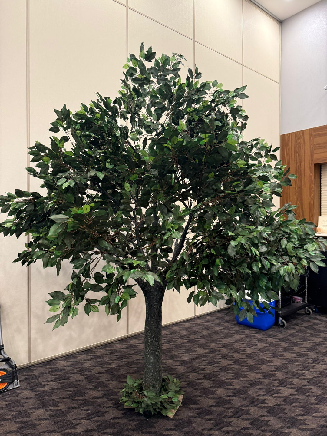 Artificial straight trunk tree in an indoor setting with a neutral wall background in an event venue