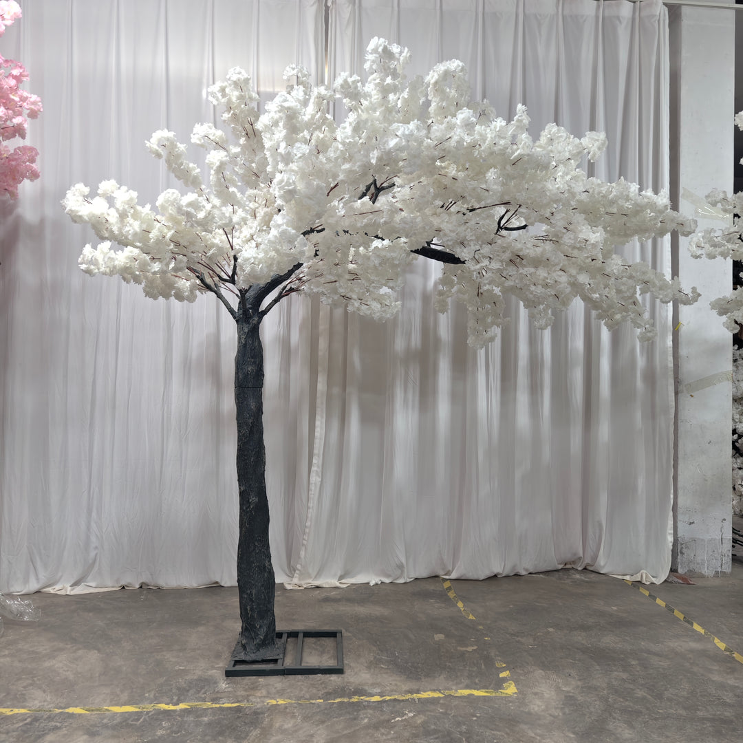Artificial Arch Cherry Blossom tree in front of white drape in a warehouse .
