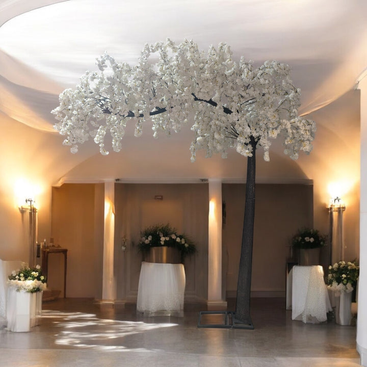 Decorative white arch cherry blossom floral arrangements in a room with soft lighting