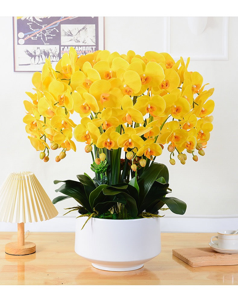 A vibrant arrangement of artificial yellow orchids with realistic petals and buds, displayed in a white ceramic pot. How can I keep artificial flowers looking fresh over time?