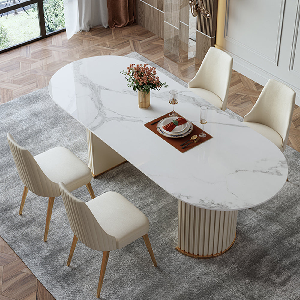 Elegant oval marble dining table with fluted base, paired with cream upholstered chairs, creating a luxurious and contemporary dining space on a plush gray rug.