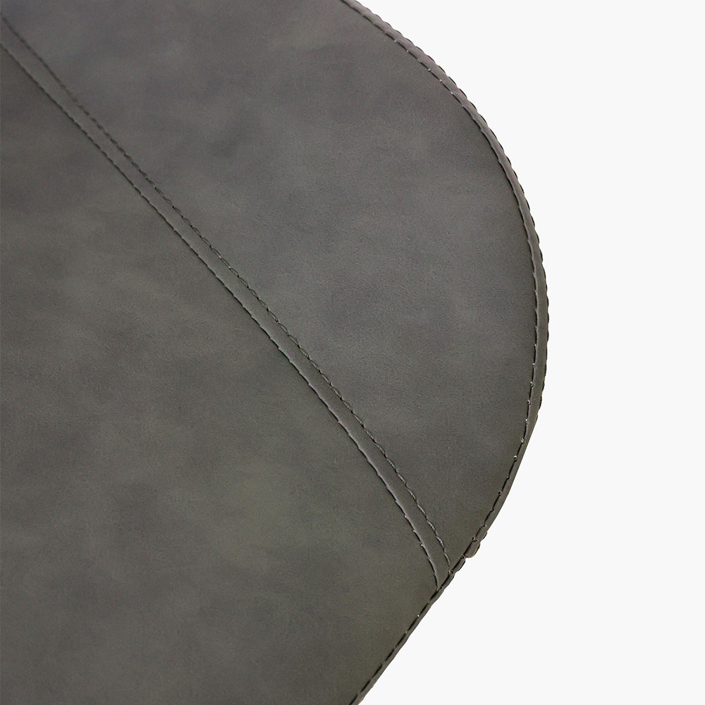 Close-up detail of a dark gray faux leather dining chair seat with fine stitching. Common questions include 'What material is best for dining chair upholstery?' and 'How do you clean faux leather dining chairs?