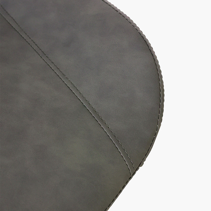 Close-up detail of a dark gray faux leather dining chair seat with fine stitching. Common questions include 'What material is best for dining chair upholstery?' and 'How do you clean faux leather dining chairs?