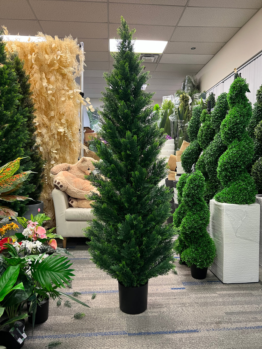 Artificial tall evergreen tree in a black pot, ideal for indoor decoration in commercial spaces or large living areas.