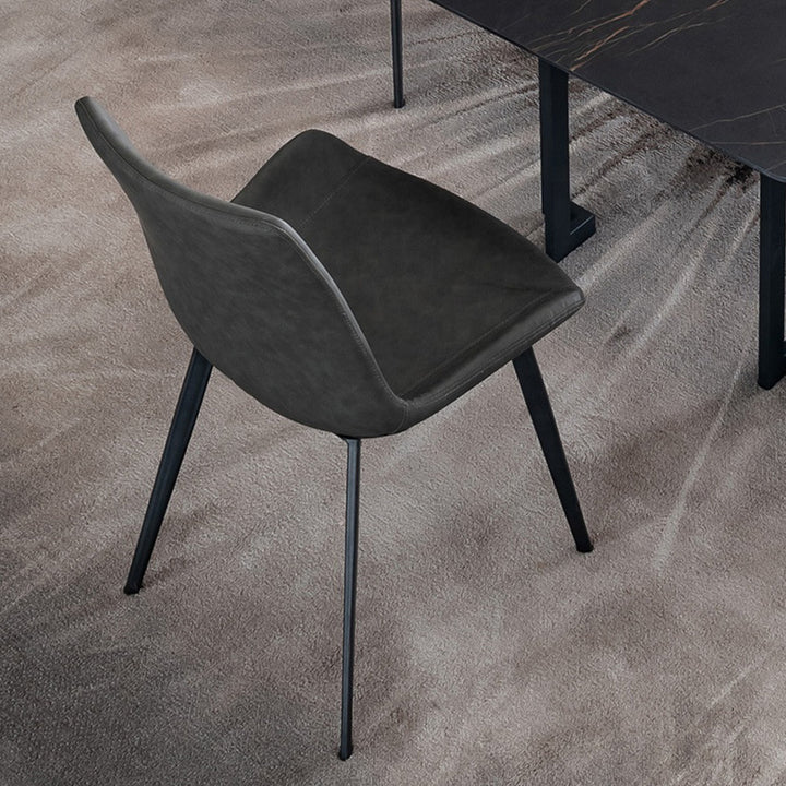 A sleek, dark gray faux leather dining chair with black metal legs, placed next to a black dining table. Frequently asked questions include 'Are faux leather chairs durable for everyday dining?' and 'What are the best ergonomic features for dining chairs?