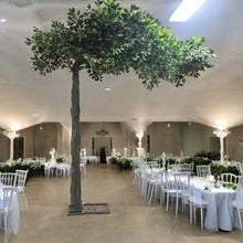 Charger l&#39;image dans la galerie, Artificial green tree with lush foliage providing a serene natural setting for weddings or events, complemented by a wooden bench and vibrant potted plants. Perfect for outdoor-themed indoor events. What are the rental options for this elegant setup?
