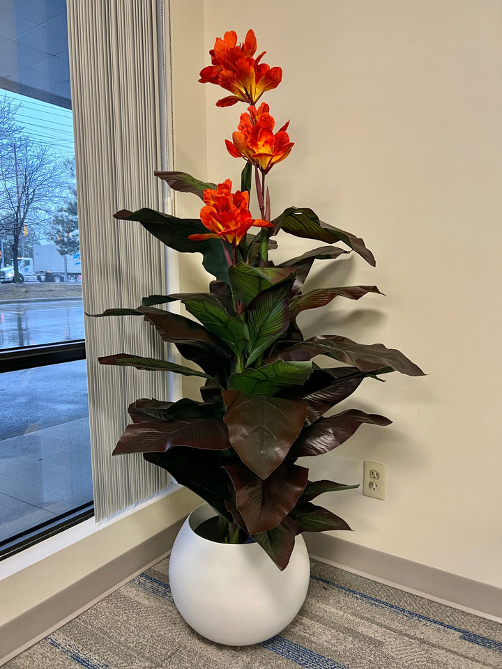 Artificial plant with striking orange blossoms and lush dark green leaves, placed in a modern white planter, adding vibrant color and a tropical feel to the office space.