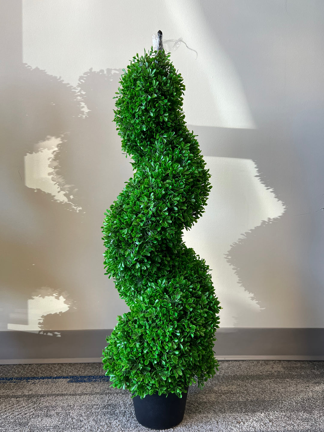 artificial spiral topiary in a sleek black pot, perfect for adding a touch of greenery and sophistication to indoor or outdoor spaces.