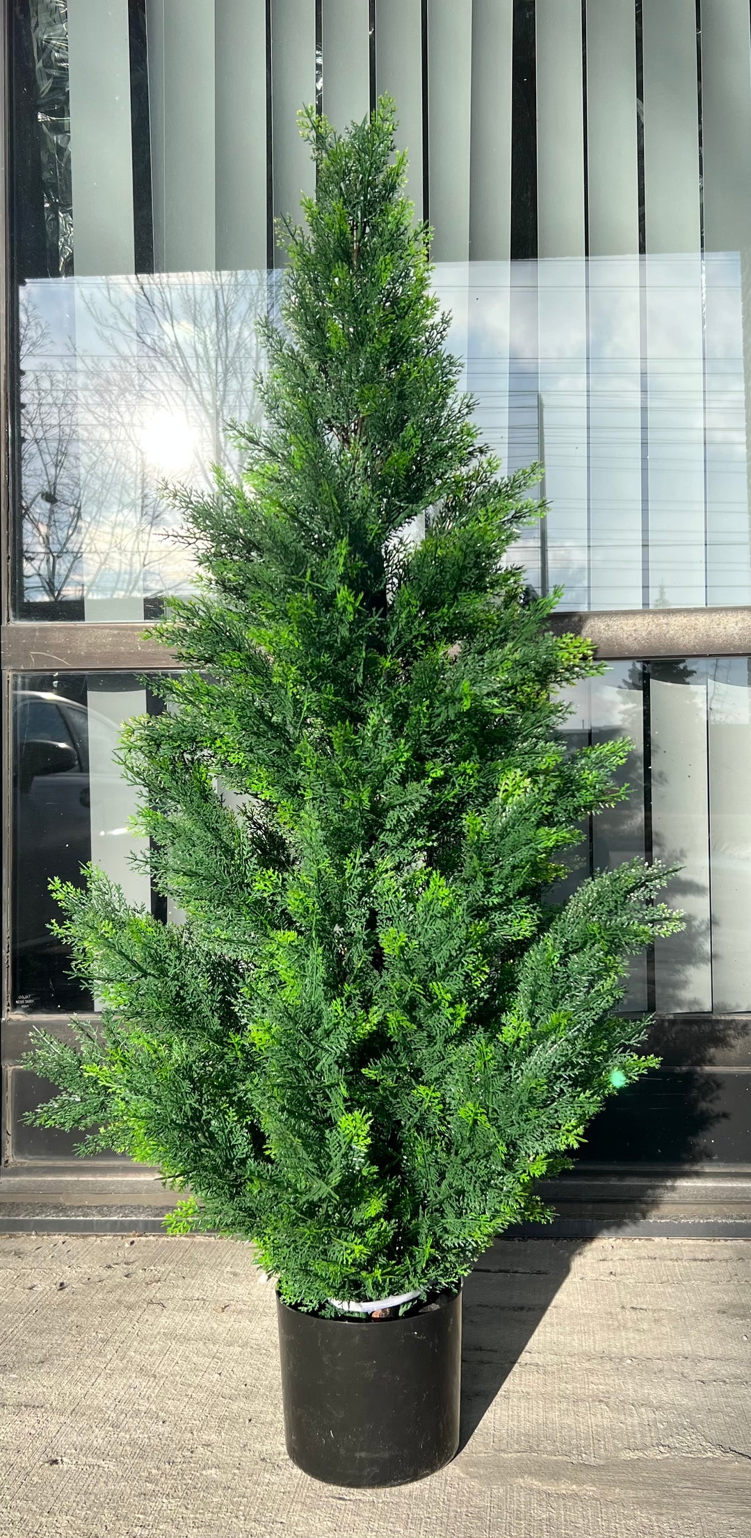 Artificial evergreen tree in a black pot with vibrant green foliage, placed outdoors, perfect for enhancing the exterior or entrance areas with a natural touch
