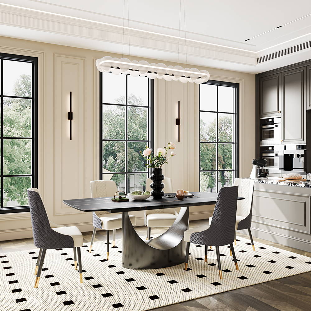 Sleek round dining table with black marble top and unique curved metal base, centerpiece of a modern kitchen with large windows and stylish decor.