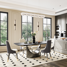 Charger l&#39;image dans la galerie, Modern dining table with a sleek black top and an artistic curved base, complemented by stylish chairs in a contemporary dining room setting
