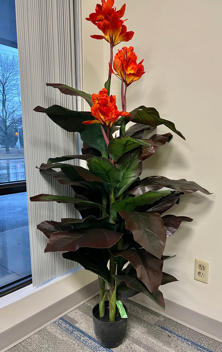 Artificial tropical plant with vivid orange flowers and broad, dark green leaves, displayed in a sleek white planter, perfect for adding a pop of color and a natural feel to indoor spaces.