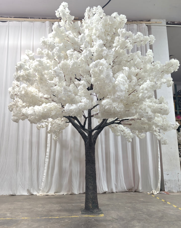 A tall artificial white blossom tree with a sturdy base, displayed against a plain white backdrop. Suitable for indoor event decor and photo backdrops. How durable are the materials used for these artificial trees?
