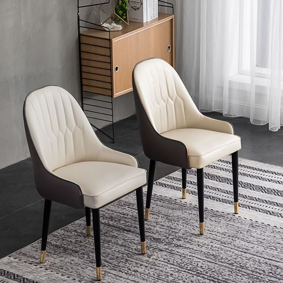 Set of two cream and brown PU leather dining chairs with black legs and gold accents, placed in a modern room. Common questions include 'Are PU leather chairs durable for everyday use?' and 'How do you maintain leather dining chairs?